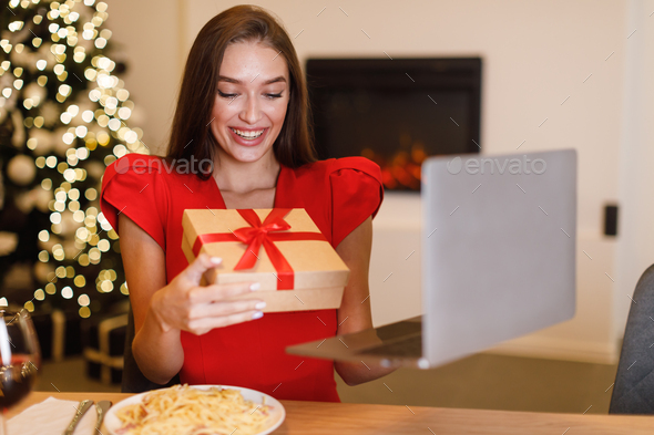 Woman showing gift box during virtual date on laptop - Stock Photo - Images