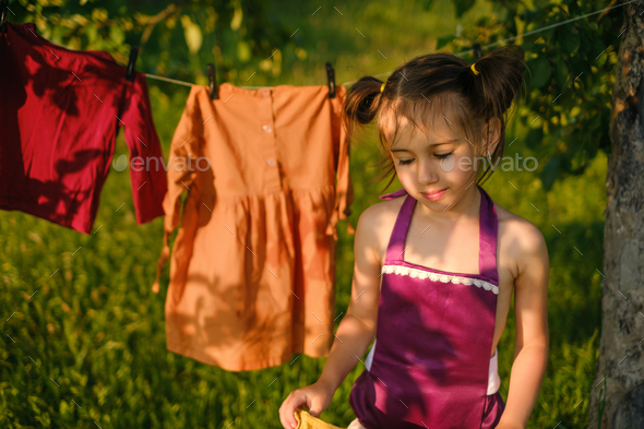 A girl carries wet clothes after washing to hang out to dry on a clothesline