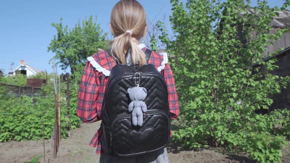 A Girl a Primary School Student with a School Bag on Her Shoulders alt