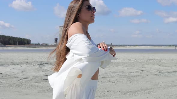 Charming Woman Standing on Beach on Windy Day