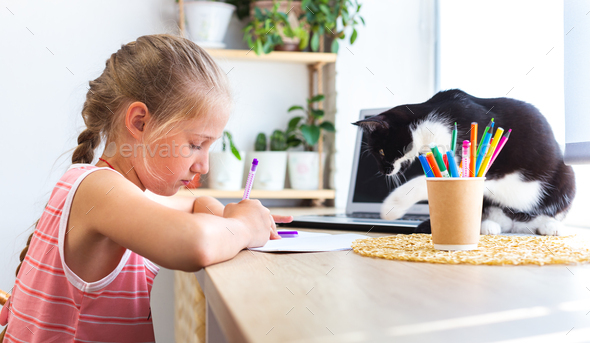 Child writing or drawing. A black cat disturb girl from doing her homework.