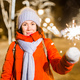 Smiling young woman wearing winter knitted clothes holding sparkler outdoors over snow background - PhotoDune Item for Sale