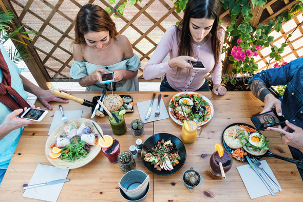Young people taking food pictures with mobile smartphone to share on social media