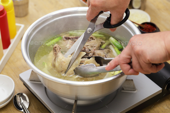 korean whole chicken soup hot pot, cutting whole chicken with scissors - Stock Photo - Images