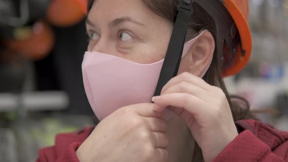 Woman in Anti Bacterial Mask Puts on a Construction Helmet