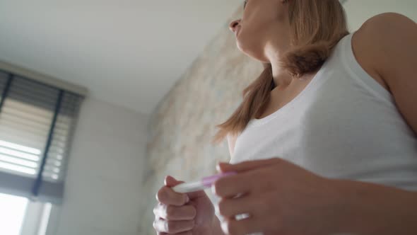Low angle view of young woman holding pregnancy test and waiting for results. Shot with RED helium c alt
