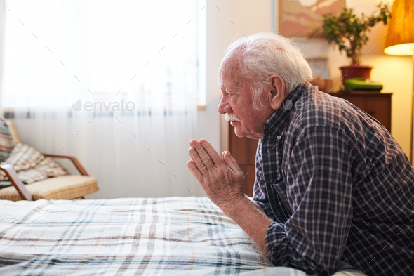 Old religious man with his hands put together in front of face
