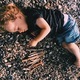 Child lying on the pebble beach - PhotoDune Item for Sale