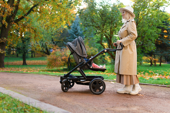Mom with a stroller in the autumn park