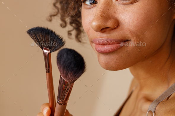 Cute lady representing cosmetic brushes in studio