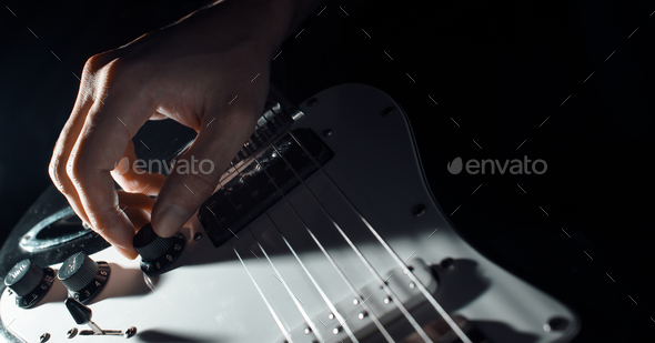 Musician playing the electric guitar. Close-up of a man\'s hand turning the volume slider on the