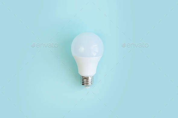 one LED light bulb on blue background. energy saving concept. minimalism