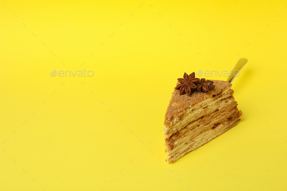 Cake spatula with honey cake on yellow background