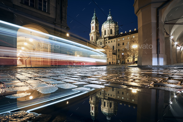 Light trail of tram passing between historic buildings