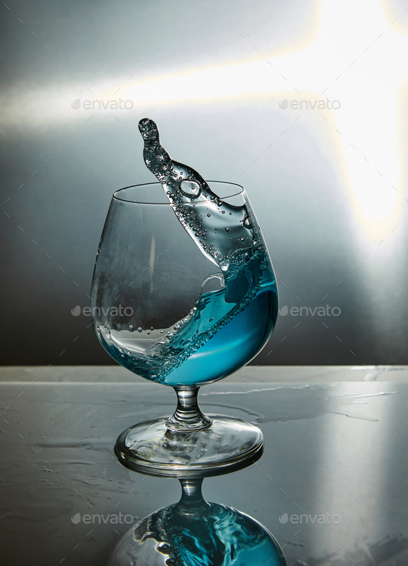 Glass of water with a wave on a grey background