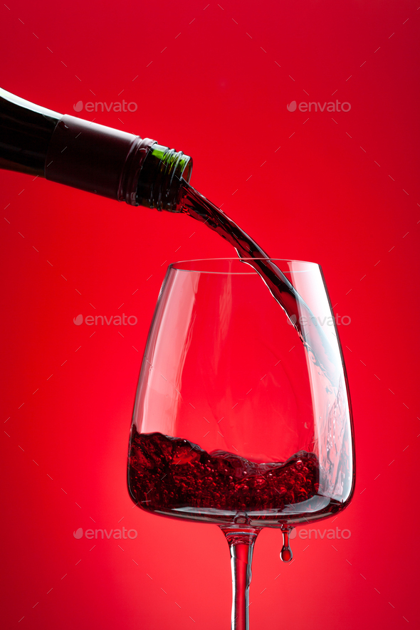 Red wine pouring from bottle into glass Stock Photo by karandaev