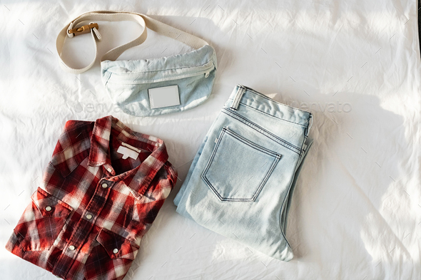 Blue Jeans, Waist Bag and Checkered Shirt on White Bedding.