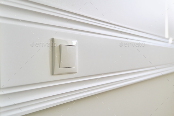 Wooden white painted panel board glued to the wall with power socket in interior close-up