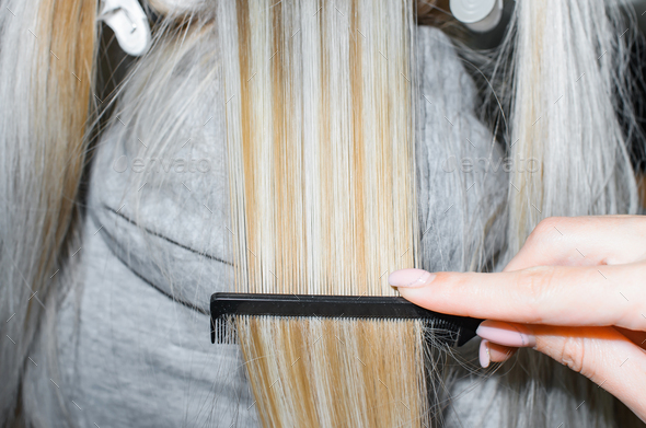 Keratin hair straightening. Hairdresser combing hair after the procedure.