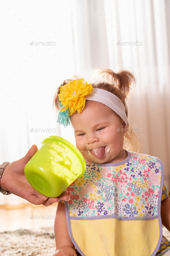Funny baby girl eating vegetable pap