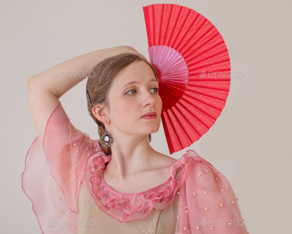 Portrait of beautiful young woman dancing flamenco. Hand with red fan raised up. Close up