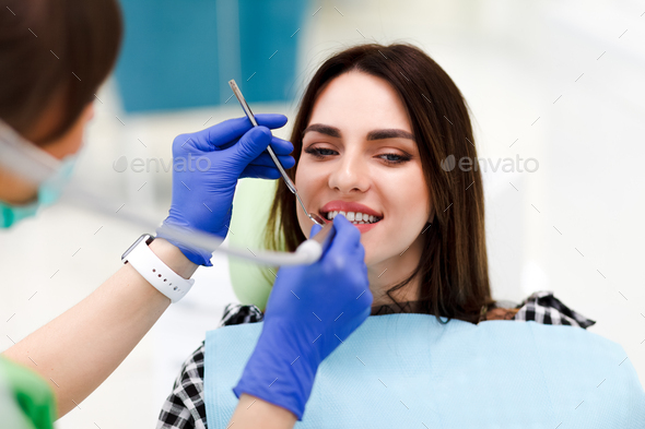 Woman at the dentistry Dentist treats teeth to his pretty patient.