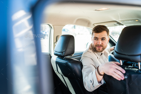 Male driver is reversing on the car. Man looks into the rear window of car - Stock Photo - Images