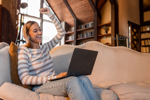 Excited woman using pc shaking clenched fist