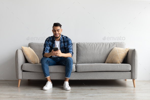 Portrait of smiling Arab man using smartphone at home