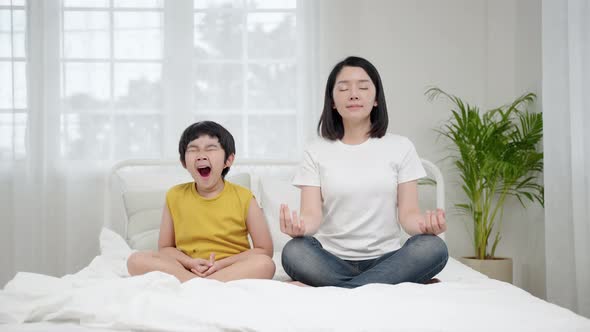 Asian family relationship, mother teaching son to meditate on bed meditation