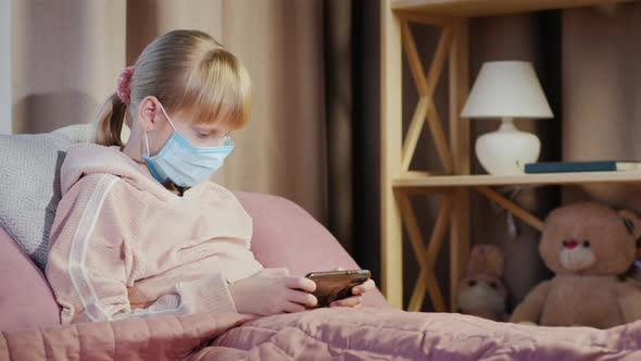 Girl in a Gauze Bandage Plays on a Smartphone alt