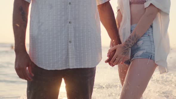 Unrecognizable Couple Holding Hands on Seashore at Sunset Close Up