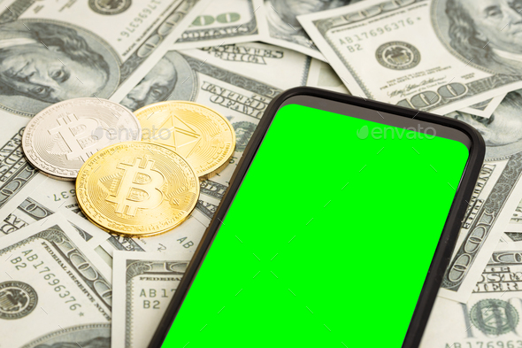 Smartphone with green screen on dollar banknotes and bitcoin