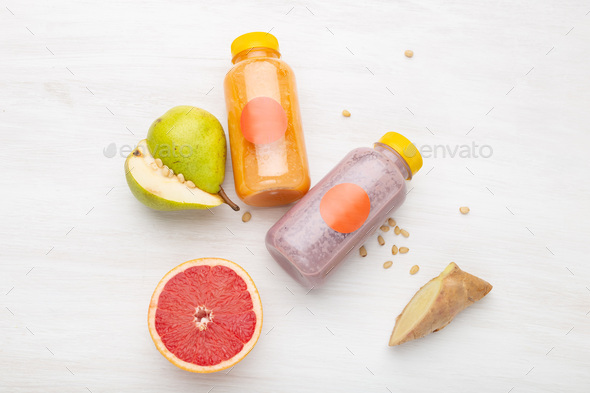 Fruit juice in a jar next to slices of pear and pine nuts standing on a white table. Concept of