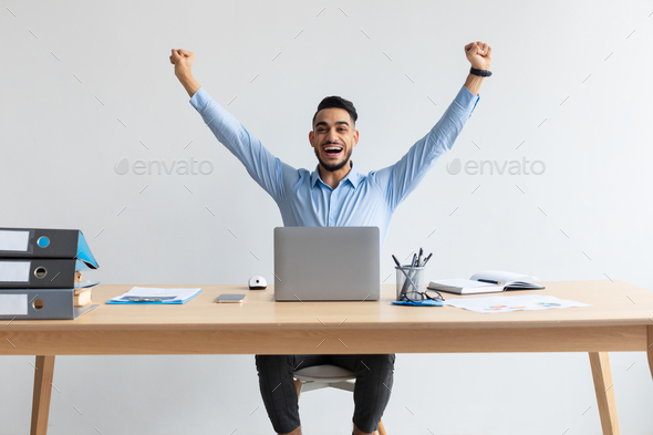 Excited man using laptop celebrating success shaking fists screaming yes
