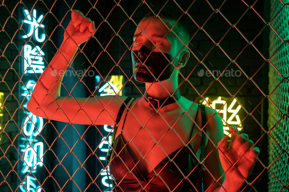 Cyberpunk girl in black leather tanktop standing behind bars