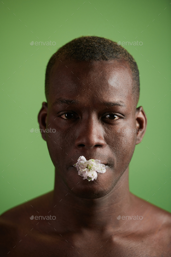 Young black man with white flower in his mouth Stock Photo by Pressmaster