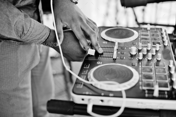 African american dj in huge white headphones creating music on mixing panel. Black and white photo.