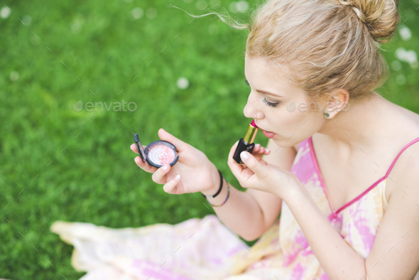 Young woman outdoor putting make up on