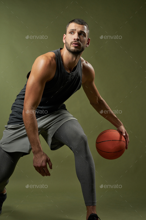 Strong basketball player with muscular body in action isolated on green