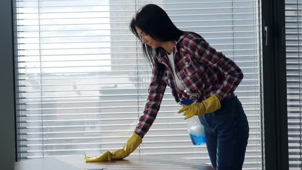 Young Woman Using Cleaning Spray on a Wooden Surface