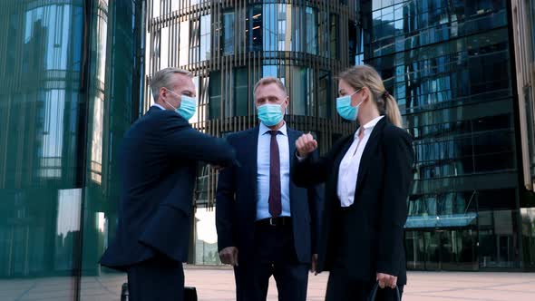 Two Businessmen in Medical Mask Meet a Businesswoman Also Wearing a Mask and Use Elbow Bumps Instead