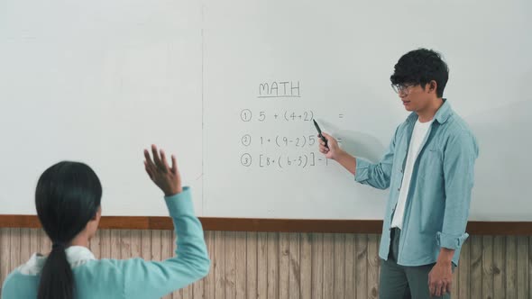 Asian male teacher teaching students at the classroom.