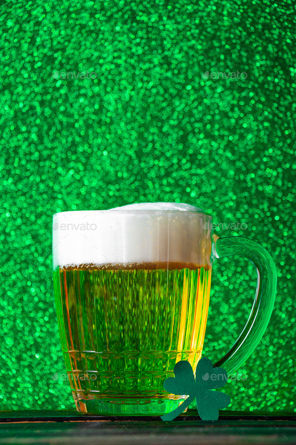 Mug of light beer with foam on green background. Traditional Irish
