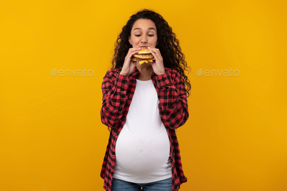 Funny Pregnant Latin Lady Holding Burger Biting Sandwich At Studio
