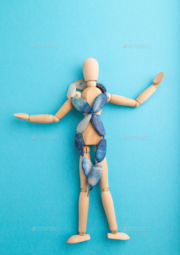 Wooden mannequin with blue agate beads on blue pastel background. copy space.