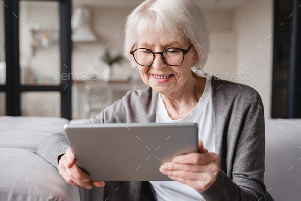 Grandmother using tablet for surfing, e-banking, e-commerce, checking pension, mortgage loan