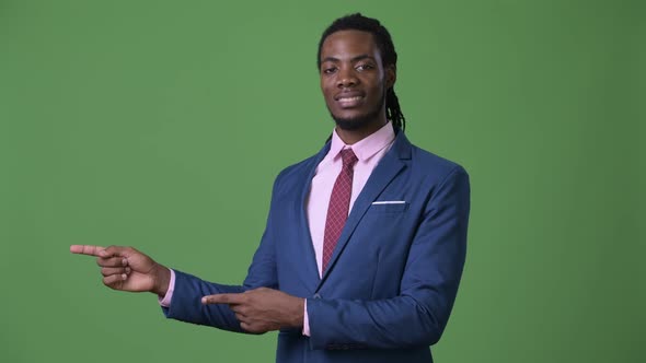 Young Handsome African Businessman with Dreadlocks Against Green Background alt