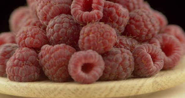 Ripe Raspberry Berries Piled on A Plate, Rotated Against a Black Background