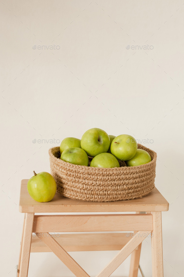 Green ripe apples in a jute basket. Cozy handicrafts in the home interior